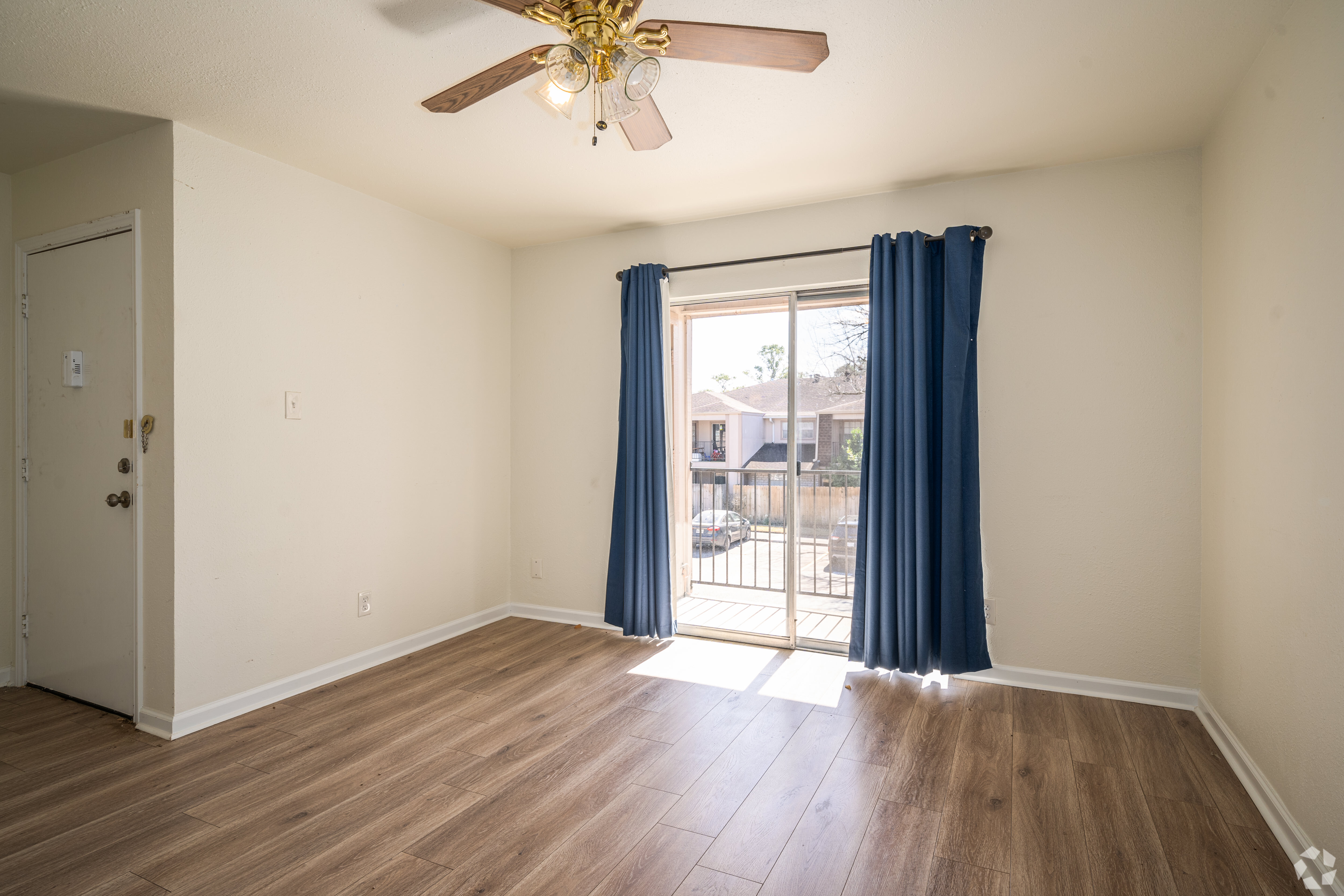 Finished apartment unit interior - living room with wood flooring and balcony
